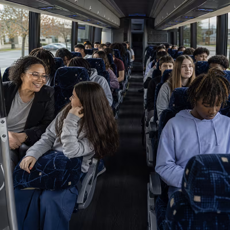 Group boarding a white charter bus for School Transportation transportation in Omaha