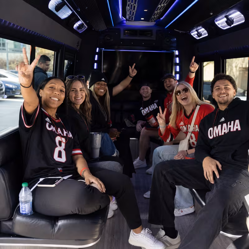 Group boarding a white charter bus for Sporting Event Transportation transportation in Omaha